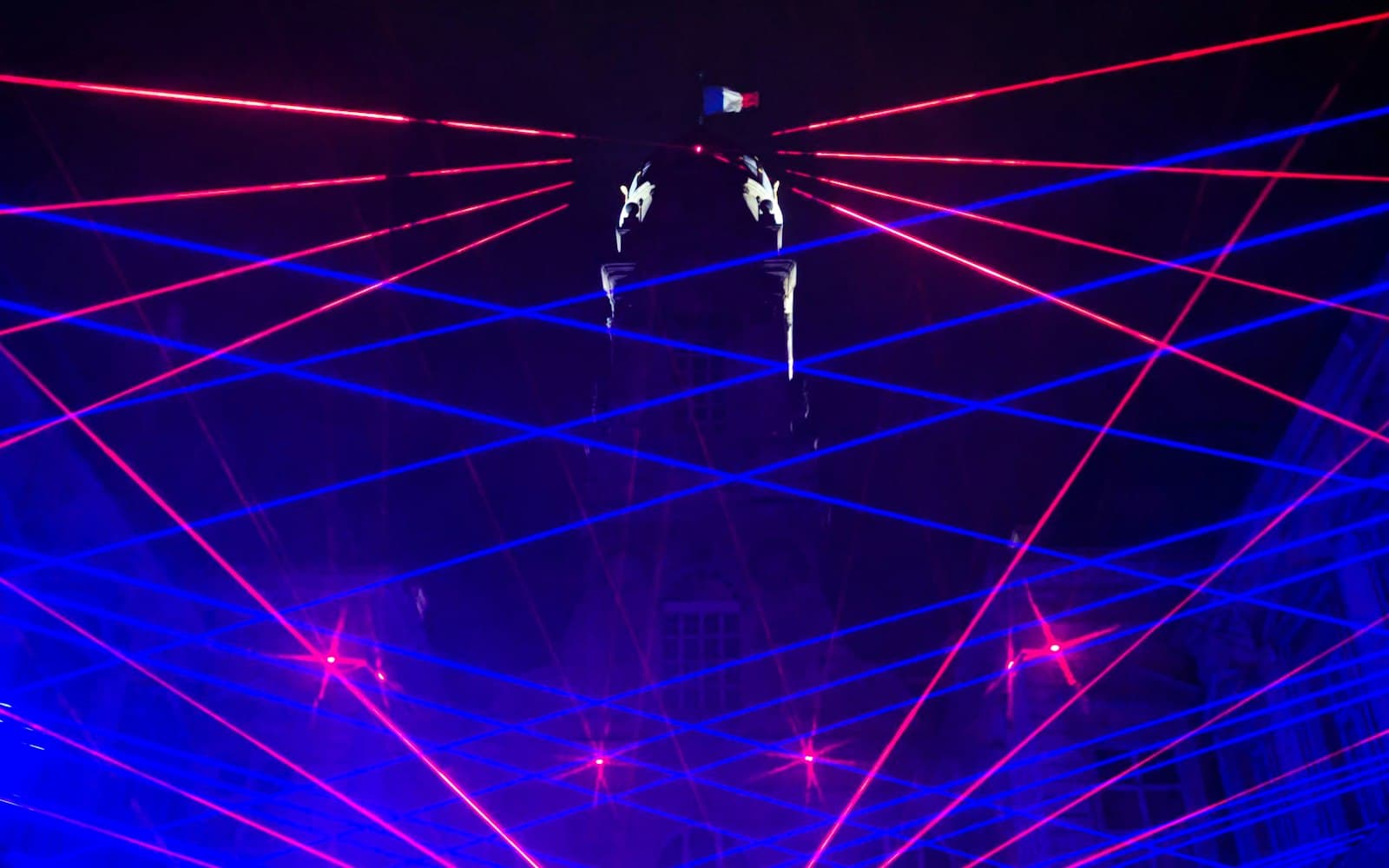 Laser beams fanning over a band on a dark stage with projected clouds behind, an example of a laser light show at a live event