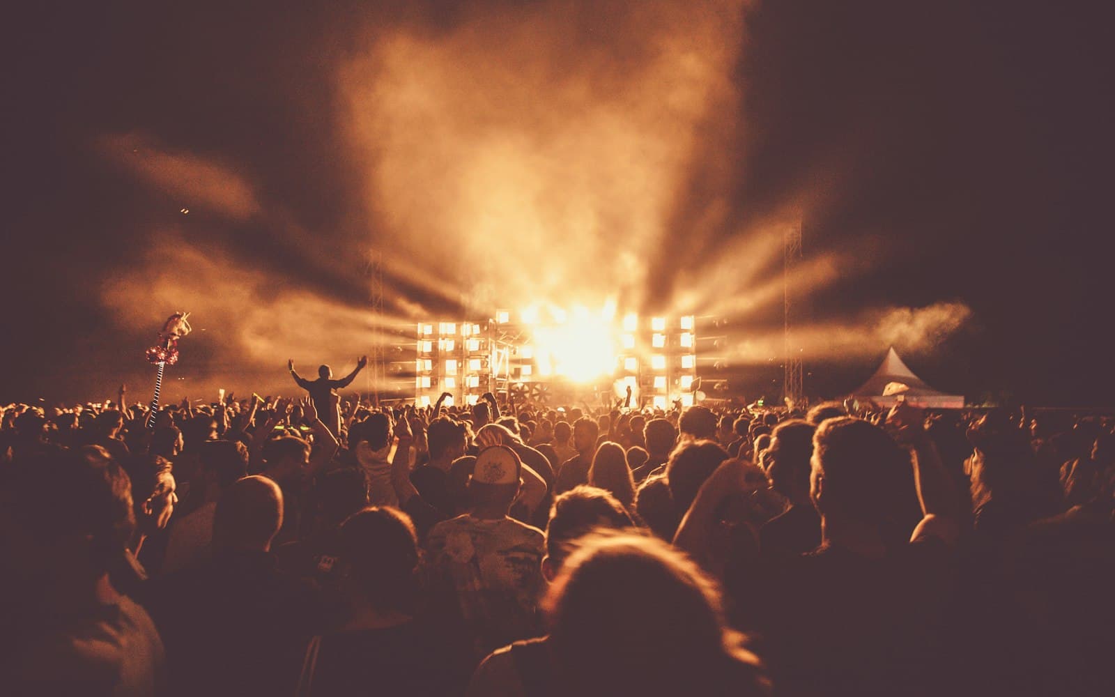 Crowd gathered at an outdoor festival main stage at night, lit by stage lighting and LED walls — the payoff of good festival talent buying