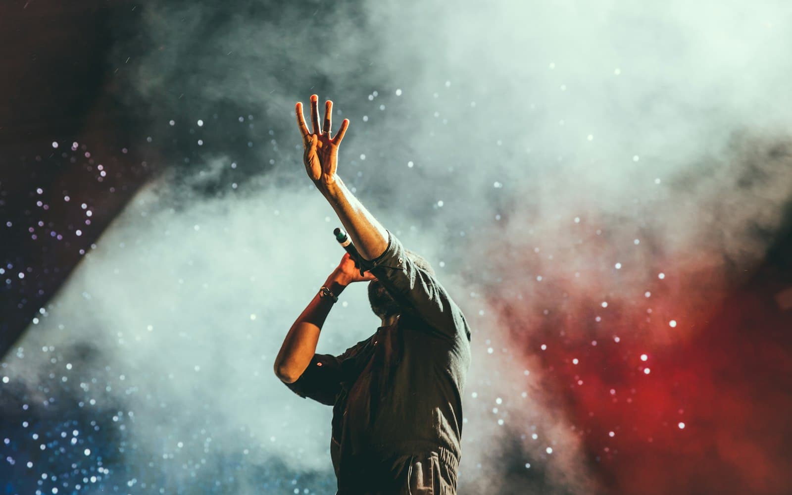 Performer silhouetted against haze and stage lighting during a festival set