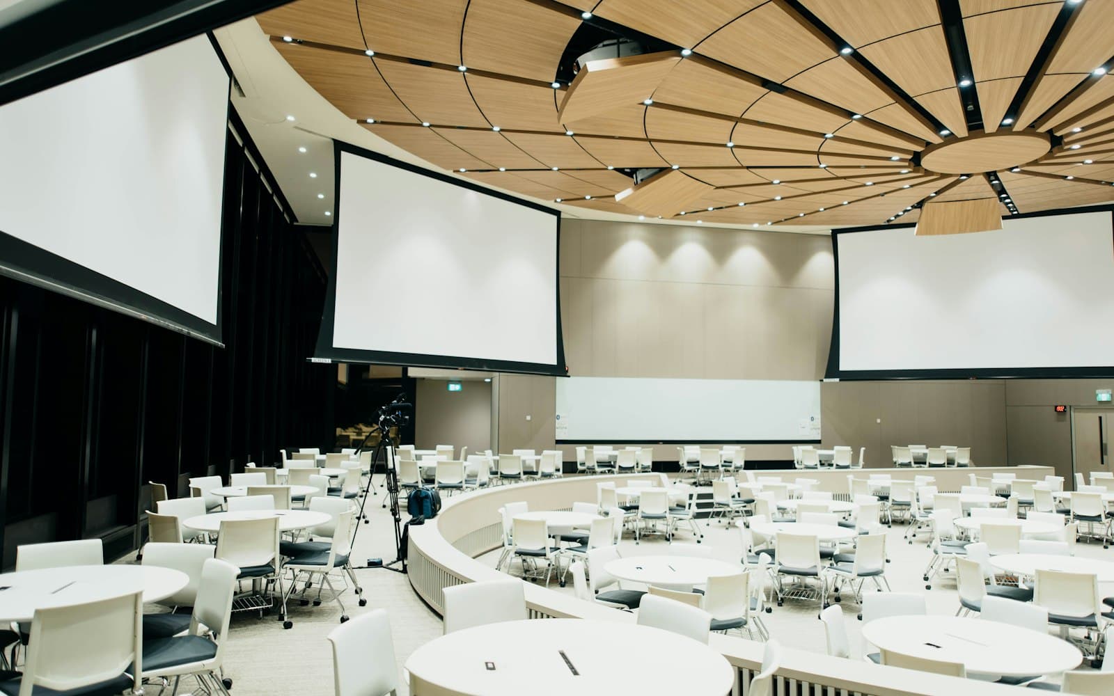 Modern Tampa ballroom set for a corporate event, with round tables, retractable projection screens, and warm overhead lighting