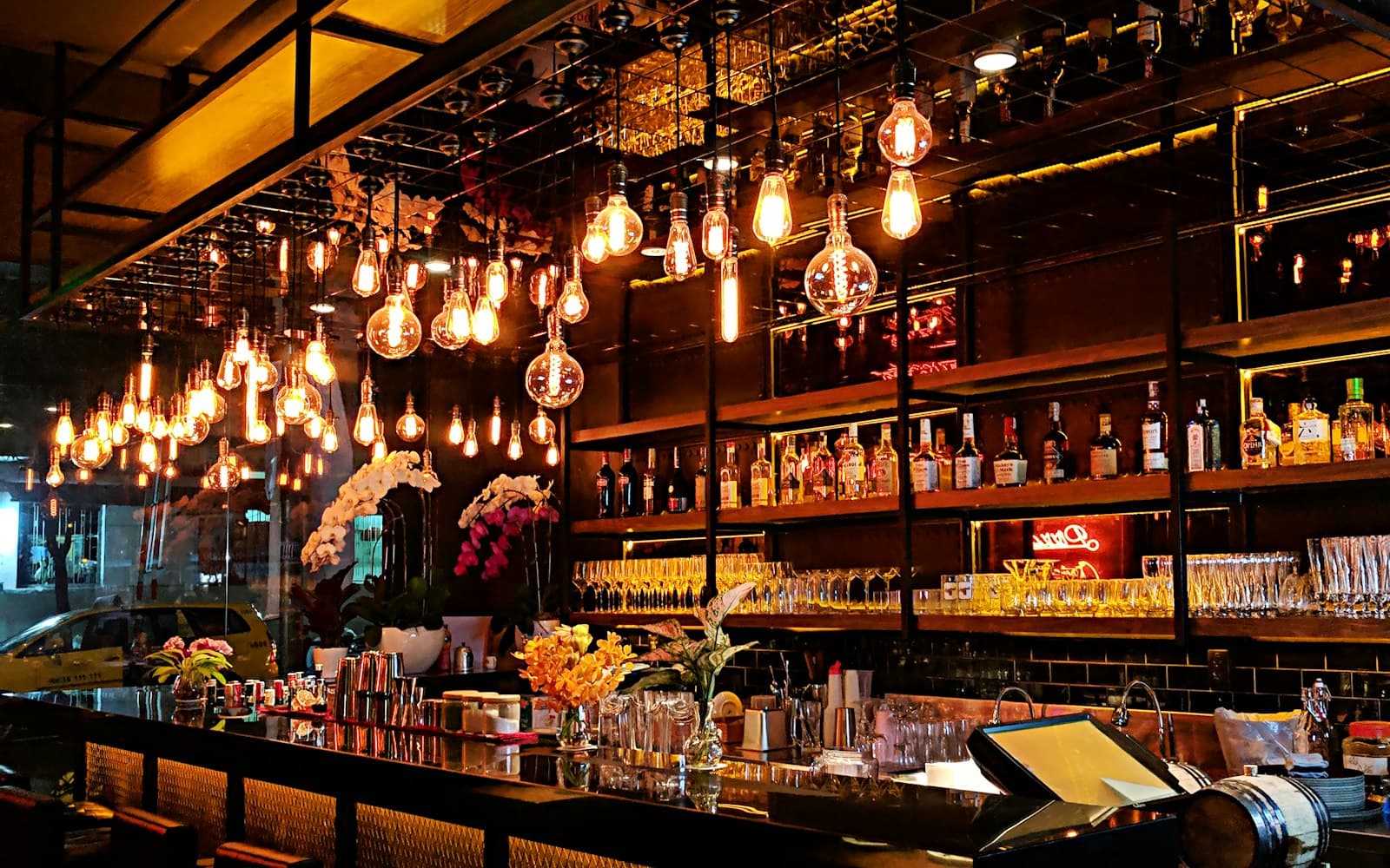 Warm amber Edison bulbs glowing over a bar at dusk — the kind of atmosphere custom playlist curation for events is designed to support